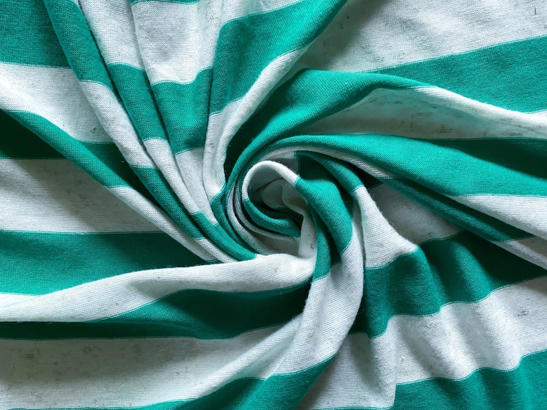 Puede incluir: Primer plano de una tela de rayas blancas y azul verdoso, doblada y retorcida en forma de espiral.