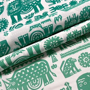 May include: White fabric with a repeating pattern of green stylized animals and plants. The design includes lions, elephants, birds, and palm trees. The fabric is folded, showing the pattern's repeat.