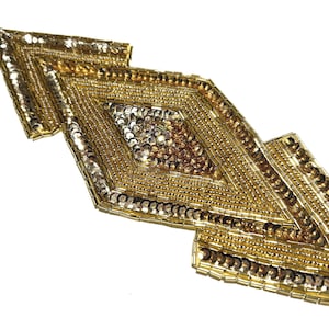 May include: Gold beaded applique with a geometric design. The applique features a central diamond shape with smaller diamond shapes on either side. The design is made with gold beads and sequins, creating a shimmering effect.