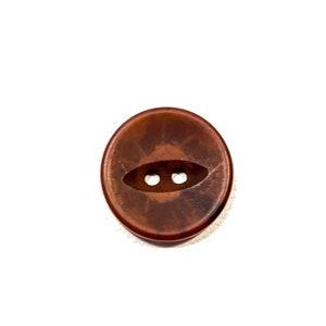 May include: A brown plastic button with two holes. The button has a slightly oval shape.
