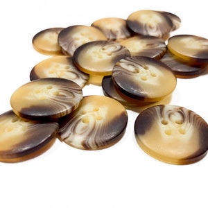 May include: A pile of brown and cream swirl patterned buttons with four holes each.