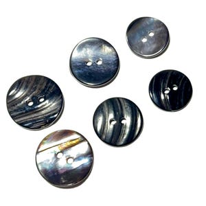 May include: A collection of six iridescent, round buttons with two holes each. The buttons vary in size and feature a swirling, pearlescent pattern in shades of gray, black, and silver. Ideal for sewing and craft projects.