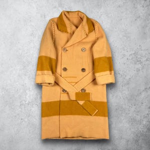 Könnte beinhalten: Ein zweireihiger Strickmantel in hellem Beige mit dunkelgelben Senfstreifen an den Ärmeln und am unteren Teil. Er verfügt über einen breiten Kragen, vier Knöpfe auf der Vorderseite und einen passenden Bindegürtel mit Ziernähten.