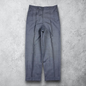 Può includere: Un paio di pantaloni grigi a pieghe con gamba dritta e orlo risvoltato. I pantaloni hanno un design classico con chiusura a bottone e zip e tasche. Il tessuto ha una trama sottile e i pantaloni sono esposti su sfondo grigio.