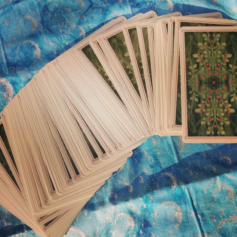 May include: A deck of tarot cards with a green and red floral design on the back of the cards. The cards are fanned out in a semi-circle.