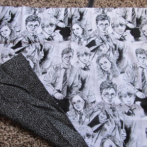 May include: Black and white fabric with a repeating pattern of Harry Potter characters. The characters are drawn in a cartoon style and include Harry Potter, Ron Weasley, and Hermione Granger.