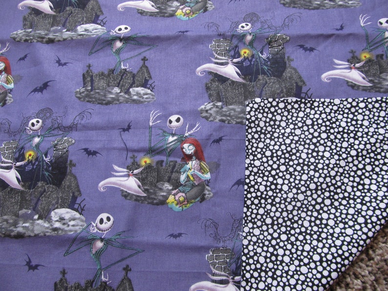 May include: Purple fabric with a repeating pattern of Jack Skellington and Sally from The Nightmare Before Christmas. The fabric has a black and white polka dot backing.