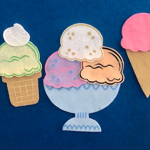May include: Three ice cream cones, one in a bowl, with a green, white, and orange scoop of ice cream. The ice cream cones are brown and have a waffle texture. The ice cream bowl is blue and white.