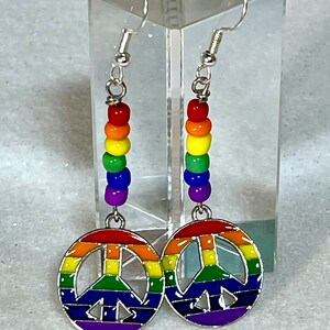 May include: Rainbow peace sign earrings with silver hooks and rainbow colored beads.