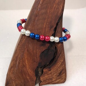 May include: A red, white, and blue beaded bracelet. The beads are round and have a glossy finish.