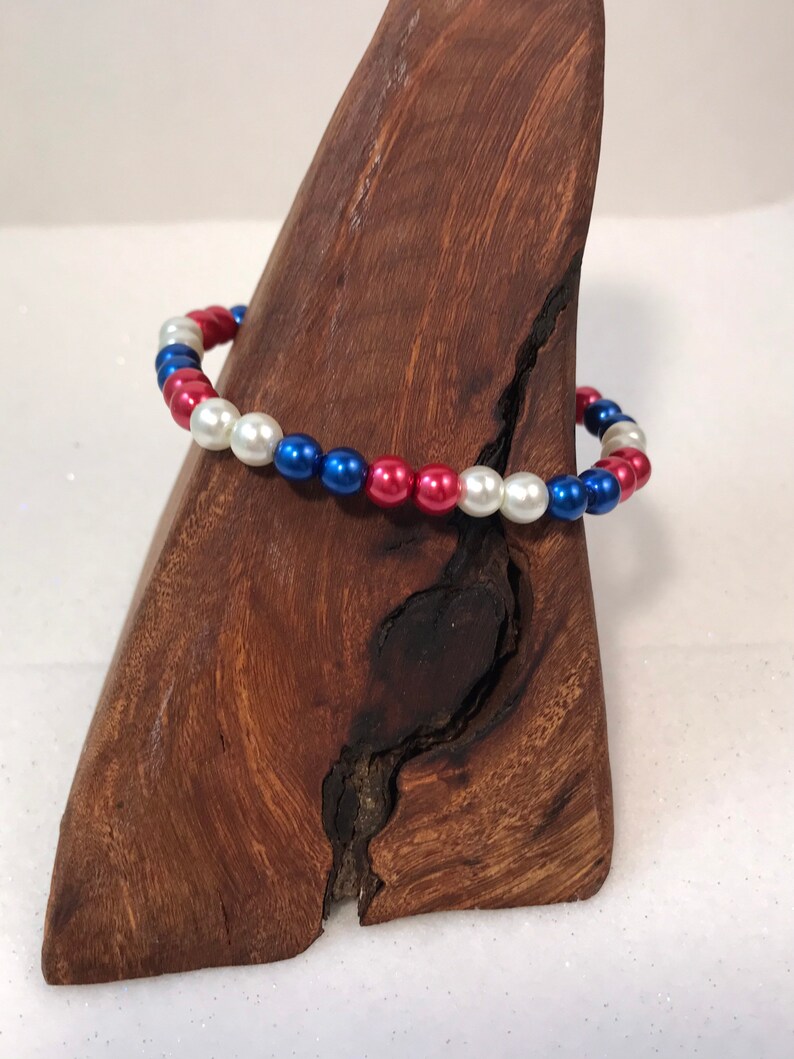 May include: A red, white, and blue beaded bracelet. The beads are round and have a glossy finish.