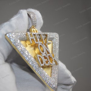 May include: A gold and silver triangle pendant with the words "Hype On Deck" set in diamonds.