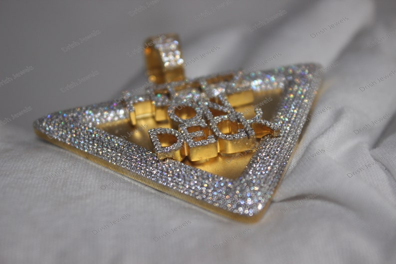 May include: A gold and silver triangle pendant with the words "Ice On Deck" set in diamonds.
