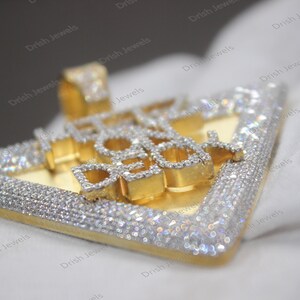 May include: A gold pendant with the words "ICE COLD" set in diamonds. The pendant is shaped like a triangle and has a diamond-encrusted border.