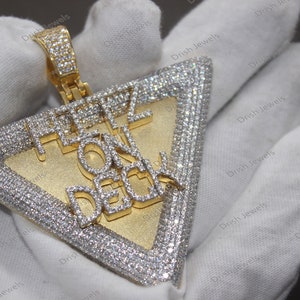 May include: A gold triangle pendant with a diamond-encrusted border and the words "FEEL ON DECK" in diamonds.