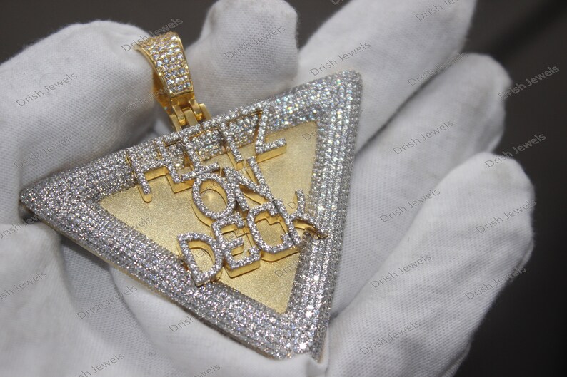 May include: A gold triangle pendant with a diamond-encrusted border and the words "FEEL ON DECK" in diamonds.