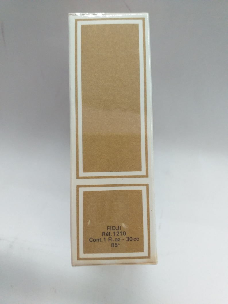 May include: A white box with a brown label. The label says "FIDJI R&eacute;f. 1210 Cont. 1 Fl. oz - 30 cc 85&deg;".