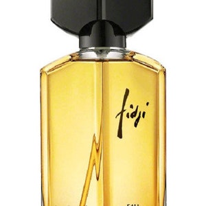 May include: A clear glass bottle of Fidji Eau de Toilette perfume by Guy Laroche. The bottle has a black cap and a gold label with the brand name and the words "Eau de Toilette".