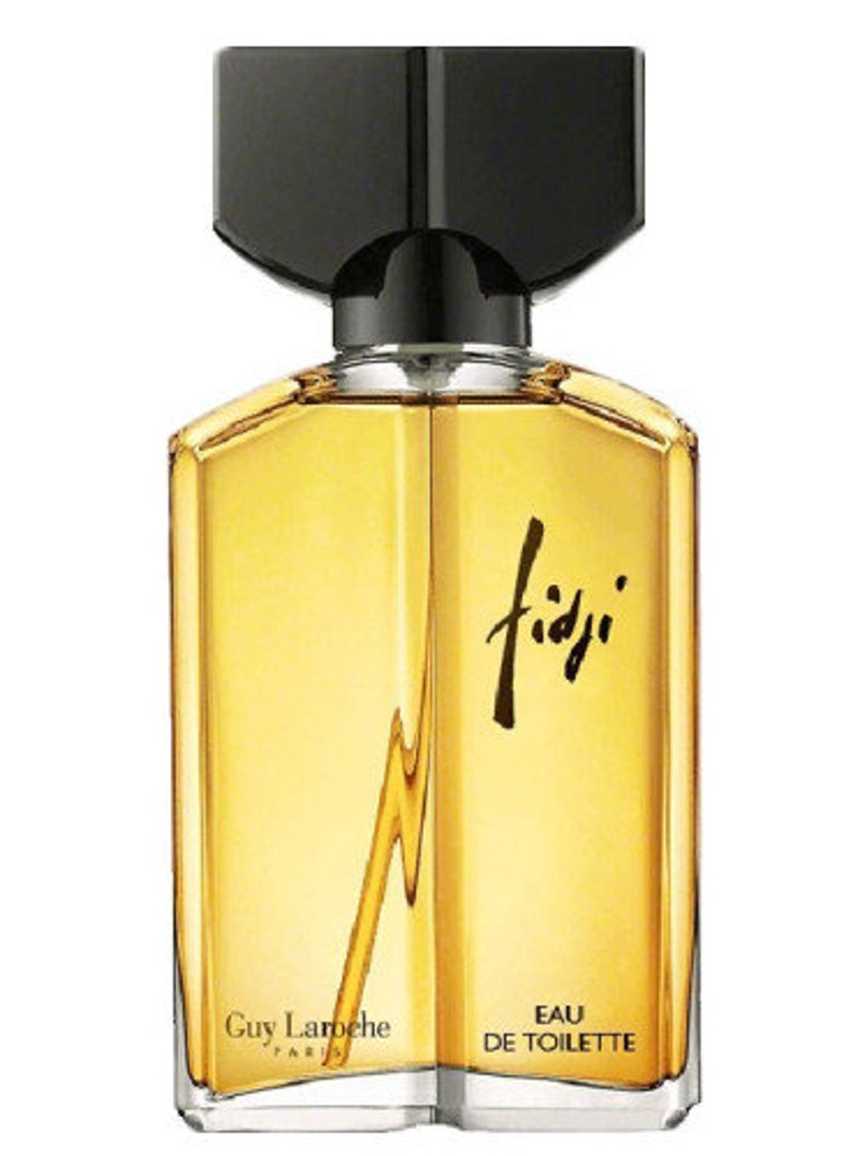 May include: A clear glass bottle of Fidji Eau de Toilette perfume by Guy Laroche. The bottle has a black cap and a gold label with the brand name and the words "Eau de Toilette".