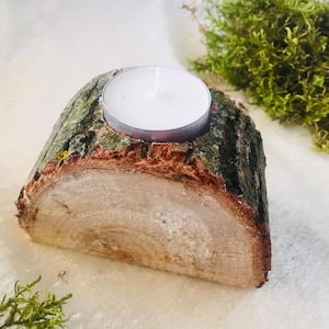 Puede incluir: Un portavelas de madera hecho de una rebanada de tronco de árbol con una vela de té blanca en su interior.