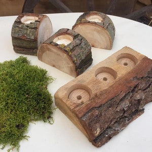 以下が含まれることがあります： 天然の樹皮の縁が付いた木製のキャンドルホルダー。画像には、3つの個別のキャンドルホルダーと、3つのキャンドルスペースを備えた長方形のホルダーが表示されています。ホルダーは明るい色の木材で作られており、素朴な外観をしています。