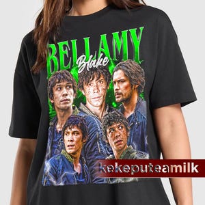 Puede incluir: Camiseta negra con un estampado gráfico verde de cuatro personajes de la serie de televisión "The 100". El gráfico presenta el texto "Bellamy Blake" y los personajes son Bellamy Blake, Clarke Griffin, Octavia Blake y John Murphy.