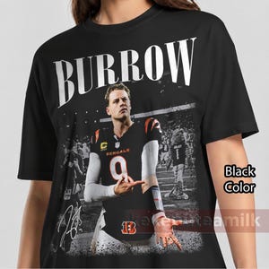 May include: A black t-shirt featuring a large graphic print of Joe Burrow in a Cincinnati Bengals jersey with the number 9. The text BURROW is printed in large white letters above the image, and a signature is visible in the lower left corner.