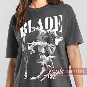 Puede incluir: Camiseta gris oscuro con la palabra "BLADE" en blanco, sobre un collage de imágenes de patinaje artístico en blanco y negro. La camiseta tiene un aspecto vintage y desgastado.