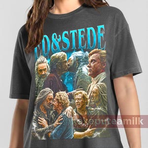 Puede incluir: Camiseta gris oscuro con un gráfico de varios hombres en varias poses y el texto "CO & STEDE" en azul claro. El gráfico tiene un aspecto vintage y desgastado. La camiseta está hecha de un material suave.