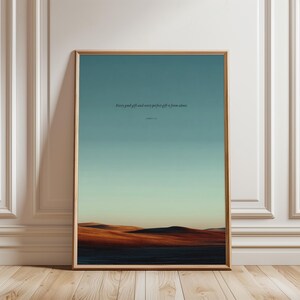 Può includere: Una stampa artistica da parete rettangolare verticale in una cornice di legno chiaro che raffigura un paesaggio di colline scure sotto un cielo sfumato dal verde acqua al giallo pallido. Il testo recita: Every good gift and every perfect gift is from above. James 1:17.