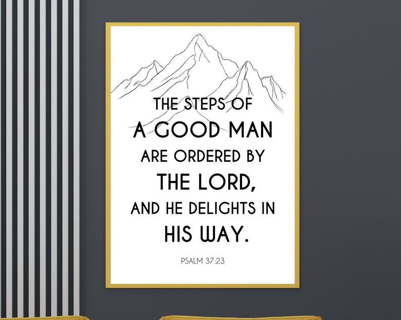 May include: A framed print with a white background and black text. The text reads "THE STEPS OF A GOOD MAN ARE ORDERED BY THE LORD, AND HE DELIGHTS IN HIS WAY." A mountain range illustration is at the top. Psalm 37:23 is at the bottom.