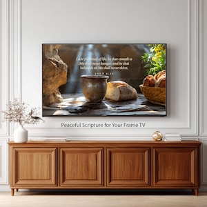 Puede incluir: Una impresión de arte digital para un televisor con marco que presenta una naturaleza muerta con pan, una olla de cerámica y una cesta de panecillos. El texto dice "Yo soy el pan de vida..." de Juan 6:35. También se incluyen las palabras "Peaceful Scripture for Your Frame TV".