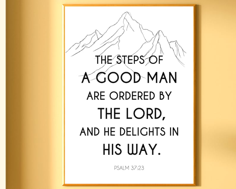 May include: A framed print with a gold border displays a black and white mountain illustration above a quote. The quote reads, "THE STEPS OF A GOOD MAN ARE ORDERED BY THE LORD, AND HE DELIGHTS IN HIS WAY." Psalm 37:23 is printed below.
