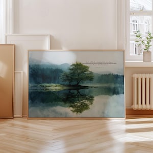 May include: A framed landscape art print featuring a serene lake scene with a tree in the center. The artwork has a natural color palette of greens, blues, and browns. The tree's reflection is visible in the water. Text is present in the upper right corner.