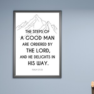 May include: A framed print with a black border, featuring a mountain illustration above the text: "THE STEPS OF A GOOD MAN ARE ORDERED BY THE LORD, AND HE DELIGHTS IN HIS WAY." The text "PSALM 37:23" is at the bottom.