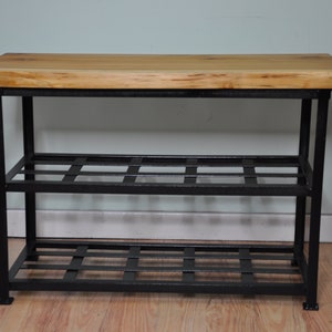 May include: A black metal shoe rack with two shelves and a wooden top. The shelves are made of a black metal grid.