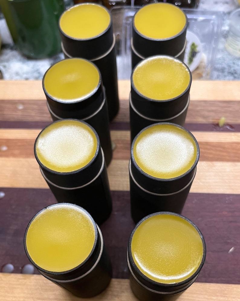 May include: A collection of cylindrical black containers with yellow tops. The containers are arranged on a wooden surface with a striped pattern. The tops have a smooth, glossy appearance, and the containers are evenly spaced.