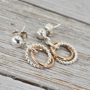 May include: Silver and rose gold earrings with a beaded design and two interlocking circles.
