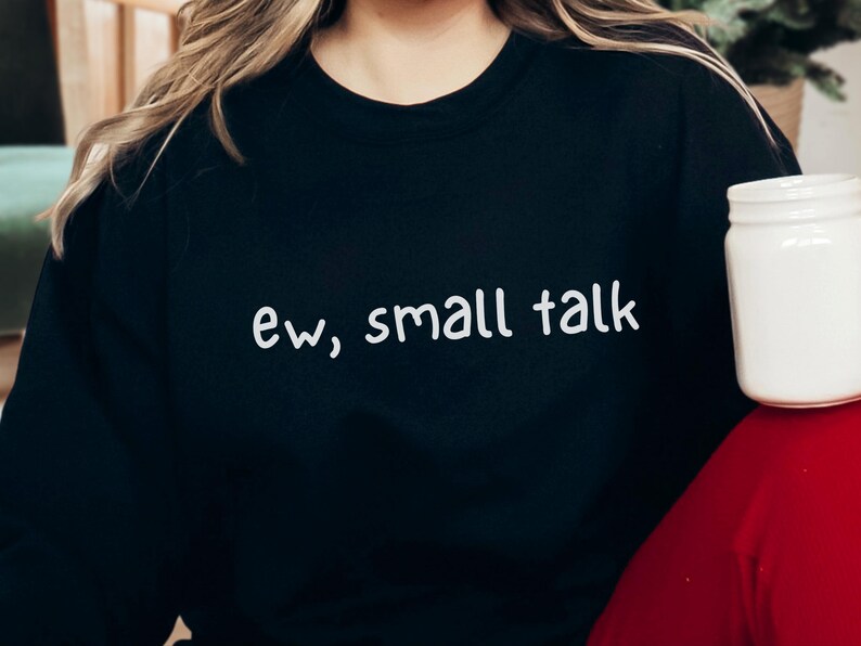 May include: Black sweatshirt with the text "ew, small talk" in white script. A white jar is visible on the right side of the image. The sweatshirt is a casual style.