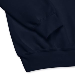 May include: Close-up of a navy blue sweatshirt sleeve and cuff. The fabric appears soft and the cuff is ribbed. The image highlights the texture and construction of the garment, suitable for casual wear.