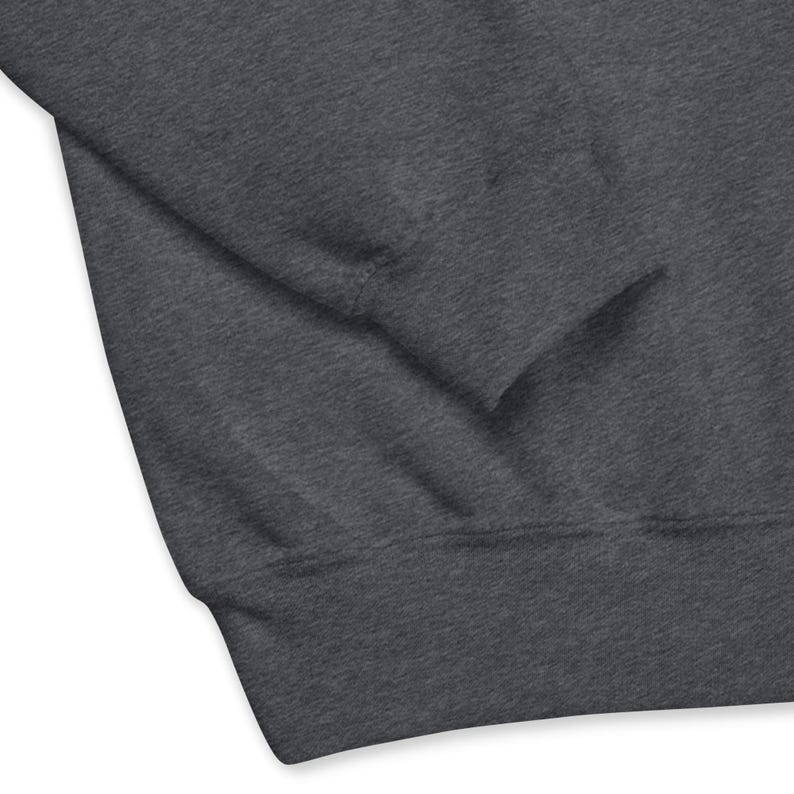 May include: A close-up of a dark gray sweatshirt. The image shows the sleeve and part of the body of the garment. The fabric appears soft and slightly textured. The sweatshirt has a ribbed cuff and hem.