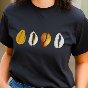 Può includere: T-shirt nero con quattro illustrazioni di conchiglie stilizzate in giallo, bianco e arancione. Le conchiglie sono disposte orizzontalmente. La maglietta è un capo casual.