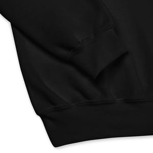 May include: Close-up of a black sweatshirt, showcasing the ribbed cuff and hem. The fabric appears soft and the garment is likely made of a comfortable material. The image highlights the details of the apparel.