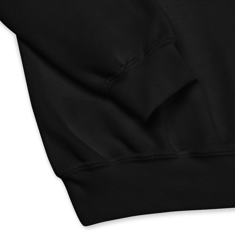 May include: Close-up of a black sweatshirt, showcasing the ribbed cuff and hem. The fabric appears soft and the garment is likely made of a comfortable material. The image highlights the details of the apparel.