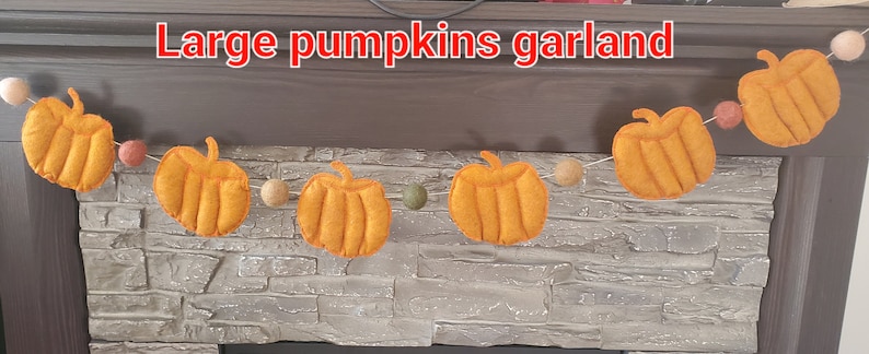 May include: A garland featuring orange felt pumpkins and small round felt balls in beige, green, and muted red colors strung along a thin cord. The text "Large pumpkins garland" is printed in white with a red outline at the top of the image.