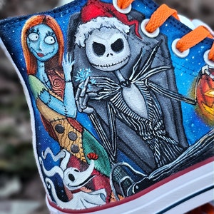 May include: Custom-painted Converse sneakers featuring characters from The Nightmare Before Christmas.  The design includes Jack Skellington, Sally, and Zero.  The background is a blue starry night.