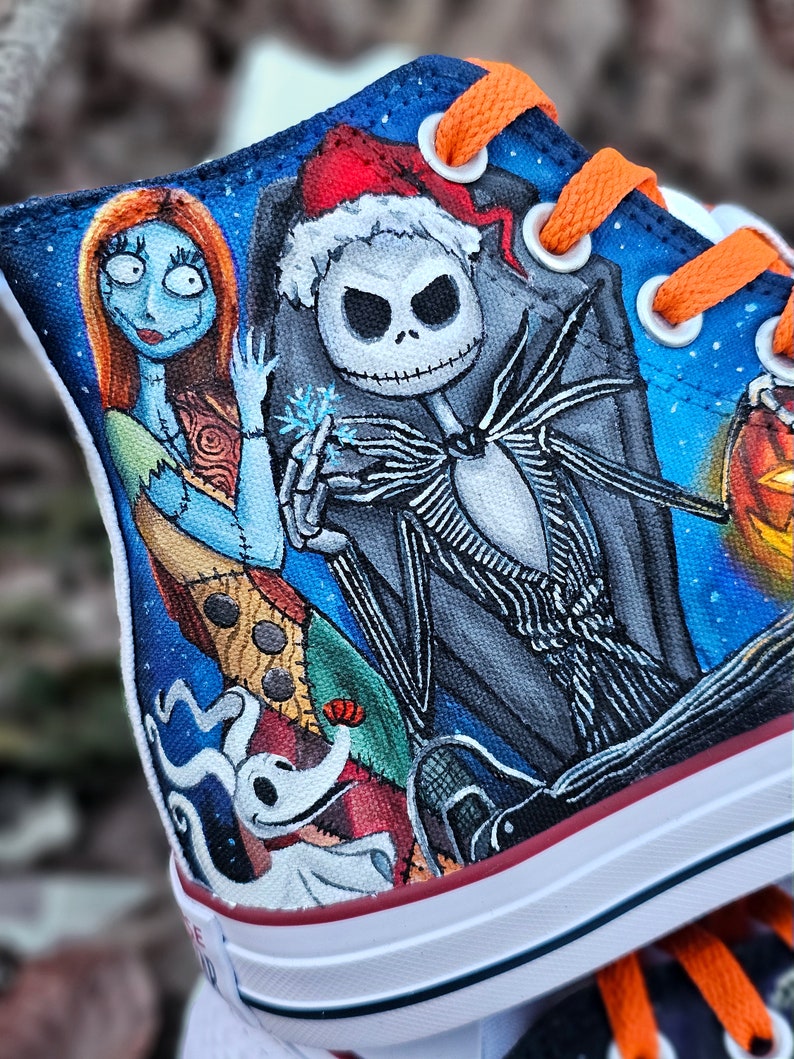 May include: Custom-painted Converse sneakers featuring characters from The Nightmare Before Christmas.  The design includes Jack Skellington, Sally, and Zero.  The background is a blue starry night.