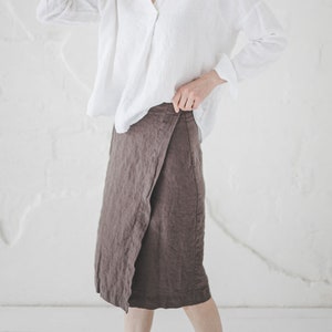 May include: A white linen shirt with a V-neck and long sleeves, paired with a brown linen wrap skirt.