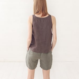 May include: A woman wearing a brown linen tank top and olive green linen shorts.