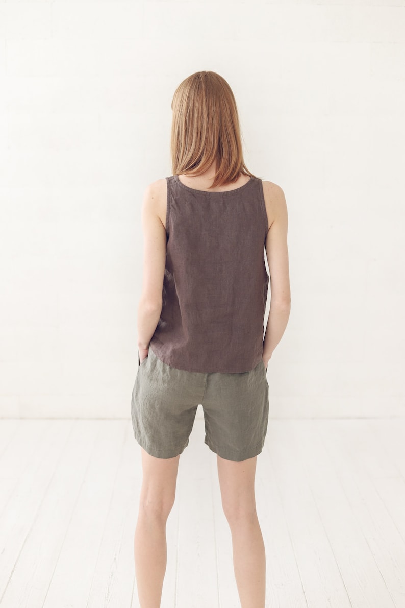 May include: A woman wearing a brown linen tank top and olive green linen shorts.